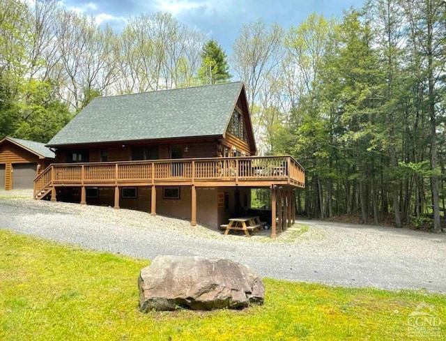 back of house with roof with shingles, a yard, a deck, and log siding