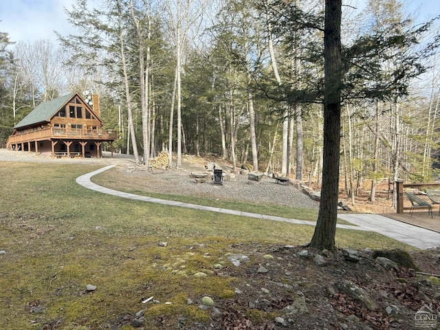 view of property's community with a view of trees, a lawn, and a wooden deck