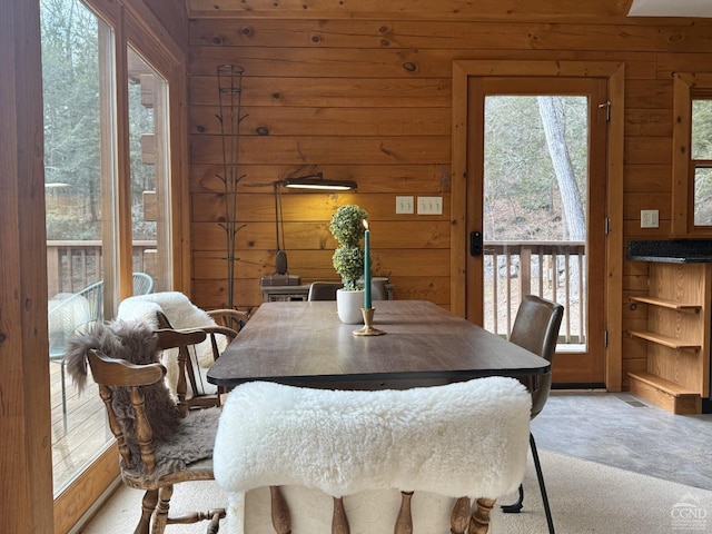 dining room with wood walls and light colored carpet