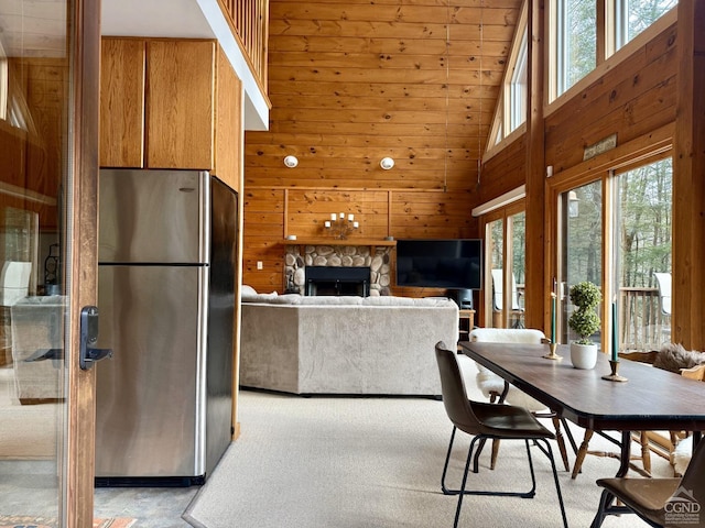 dining area with a stone fireplace, wooden walls, and a high ceiling