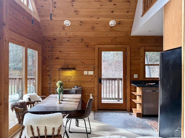 dining area with high vaulted ceiling and wood walls