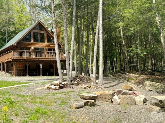 back of house with a deck, a forest view, and a chimney