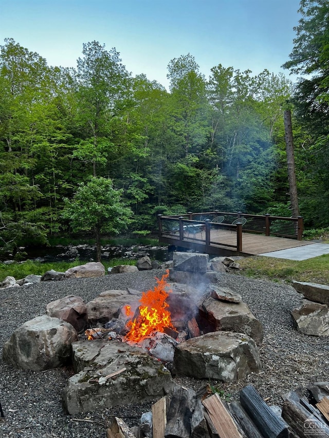 view of property's community featuring an outdoor fire pit, a deck, and a wooded view