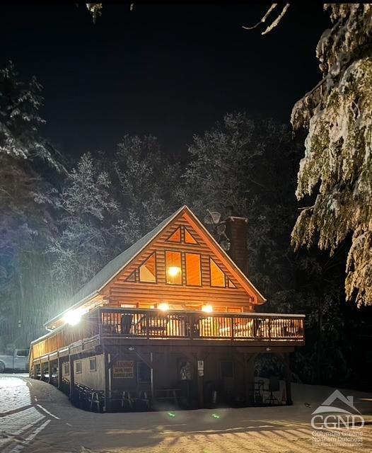 back of house at night with a wooden deck