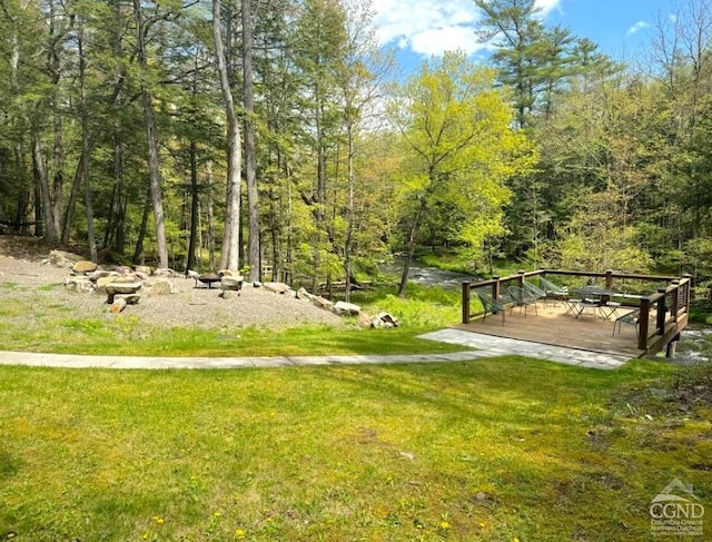 view of community featuring a forest view, a yard, and a wooden deck