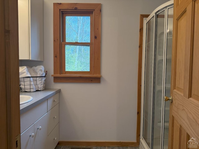 full bathroom featuring a shower stall, vanity, and baseboards