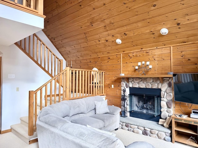 living room featuring carpet floors, a stone fireplace, wooden ceiling, baseboards, and stairs