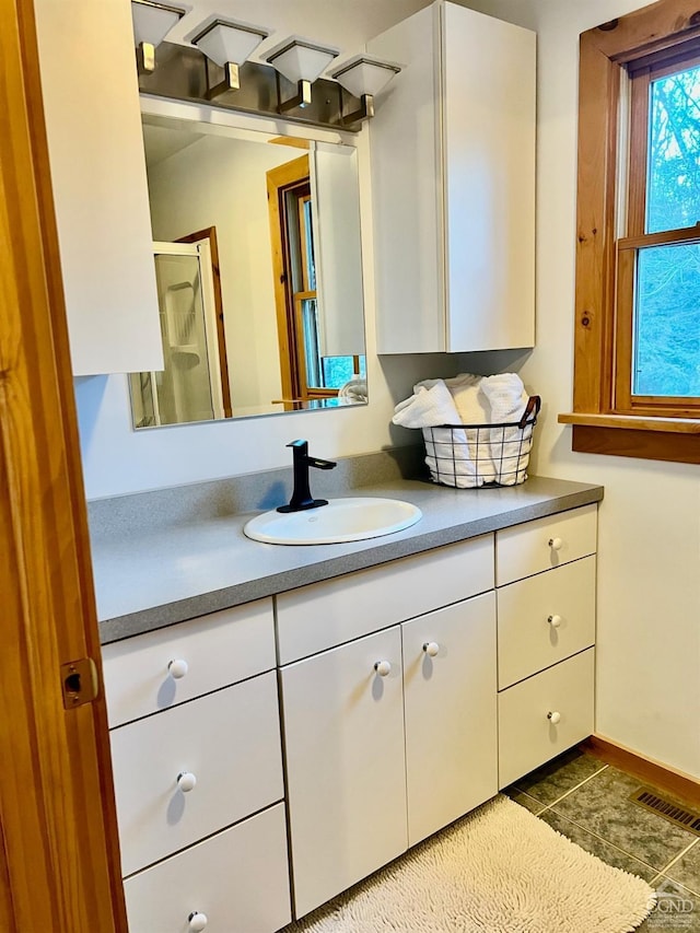 bathroom with visible vents, a shower with shower door, vanity, baseboards, and tile patterned floors