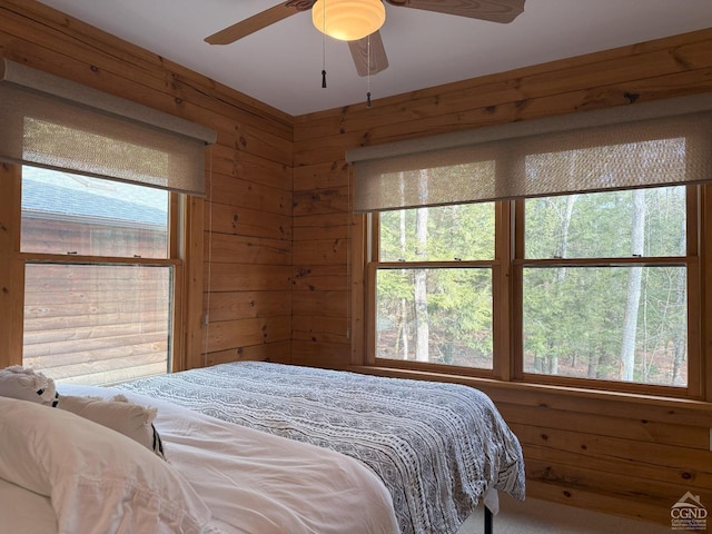 bedroom with a ceiling fan and wooden walls