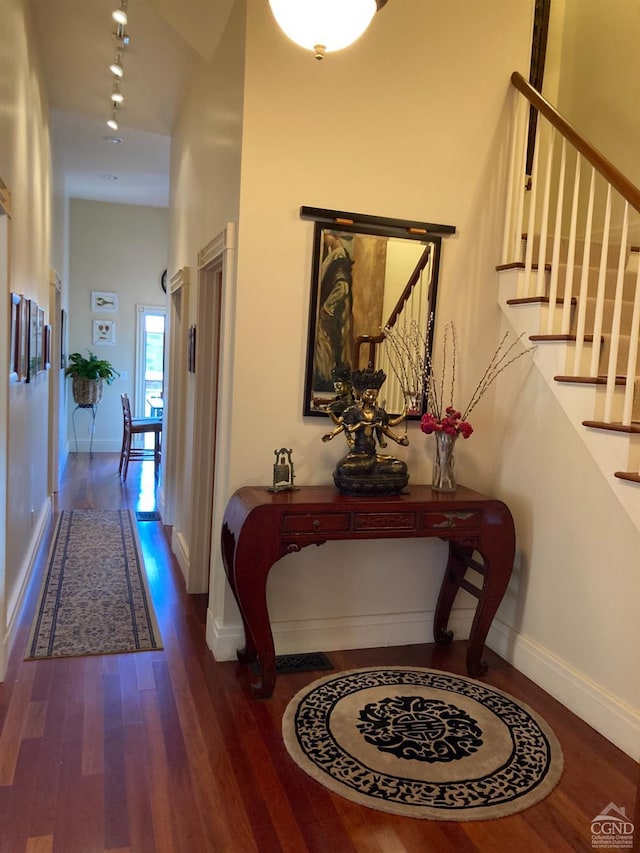 hallway featuring dark hardwood / wood-style flooring and a towering ceiling