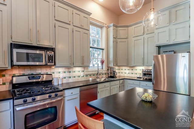 kitchen featuring appliances with stainless steel finishes, backsplash, decorative light fixtures, and sink