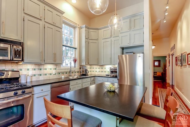 kitchen with a kitchen breakfast bar, tasteful backsplash, stainless steel appliances, sink, and pendant lighting