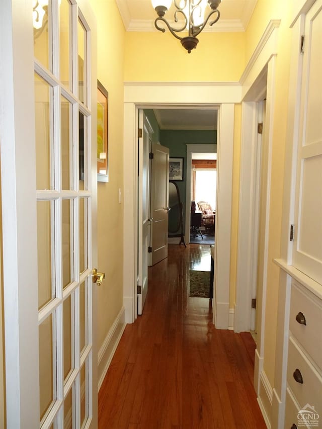 hall with ornamental molding, dark wood-type flooring, and an inviting chandelier