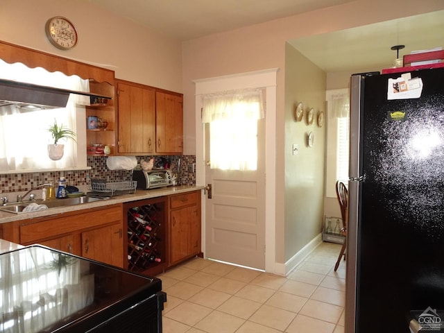 kitchen with sink, stainless steel fridge, light tile patterned floors, tasteful backsplash, and range