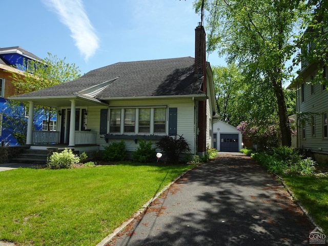 view of front of property featuring a porch, a garage, an outbuilding, and a front yard