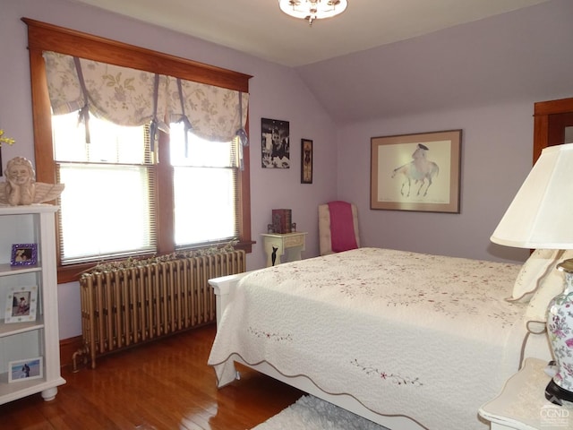 bedroom featuring radiator heating unit, vaulted ceiling, and wood-type flooring