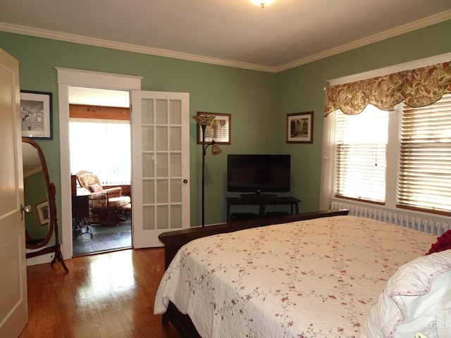 bedroom featuring hardwood / wood-style floors, radiator heating unit, and crown molding