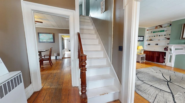 stairs with hardwood / wood-style flooring, crown molding, and built in shelves