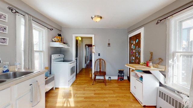 kitchen with sink, light wood-type flooring, radiator, electric stove, and white cabinets