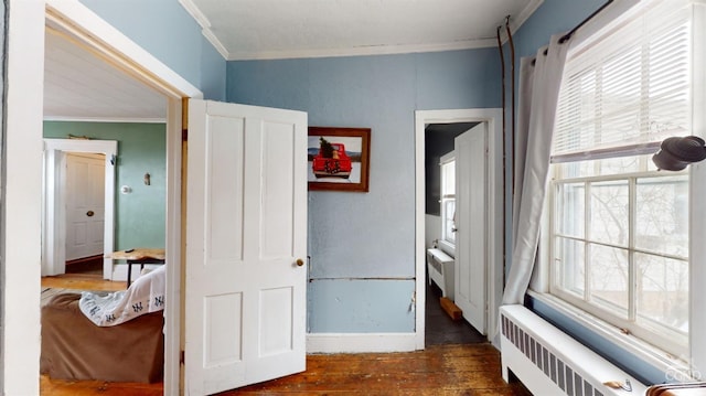 interior space with dark wood-type flooring, ornamental molding, and radiator