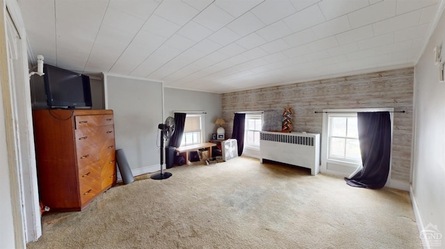 bedroom with ornamental molding, carpet flooring, radiator, and wood walls