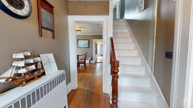 stairs featuring hardwood / wood-style flooring and radiator heating unit