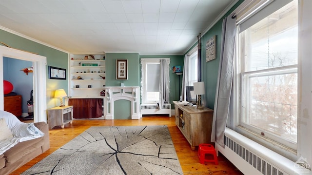 bedroom featuring radiator heating unit, ornamental molding, and light hardwood / wood-style floors