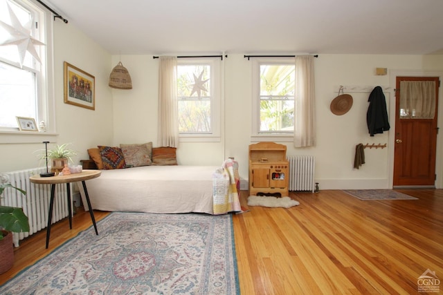 bedroom featuring radiator heating unit and wood-type flooring