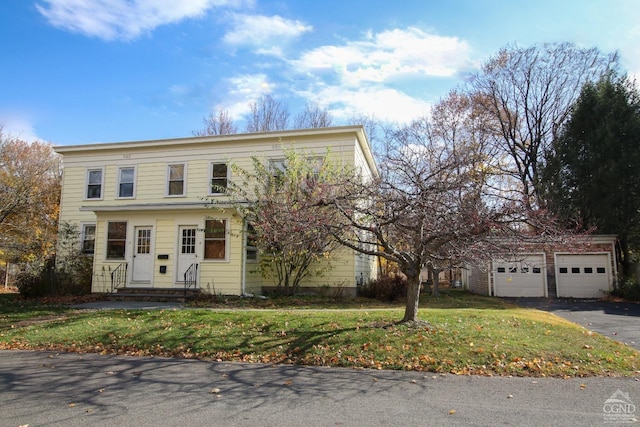 view of front facade featuring an outbuilding, a front yard, and a garage