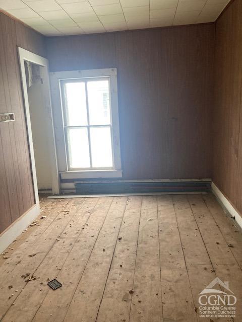 empty room with wood walls and light hardwood / wood-style floors