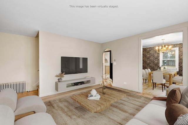 living room featuring a chandelier, radiator heating unit, and light hardwood / wood-style flooring