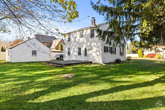 rear view of house with a chimney, central air condition unit, a deck, and a lawn