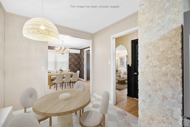 dining space featuring light hardwood / wood-style flooring, crown molding, a wall unit AC, and a chandelier