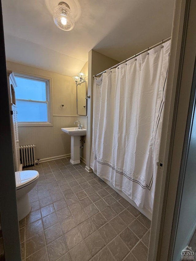 full bathroom featuring toilet, radiator heating unit, a shower with curtain, a sink, and wainscoting