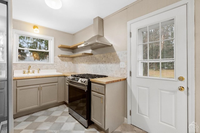 kitchen featuring backsplash, wooden counters, stainless steel range with gas cooktop, sink, and extractor fan