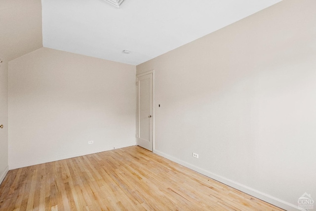 spare room with baseboards, vaulted ceiling, and wood finished floors