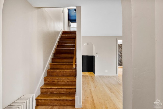 stairs featuring hardwood / wood-style flooring and radiator