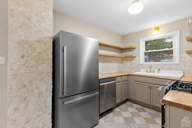 kitchen with butcher block countertops, tasteful backsplash, sink, and stainless steel appliances