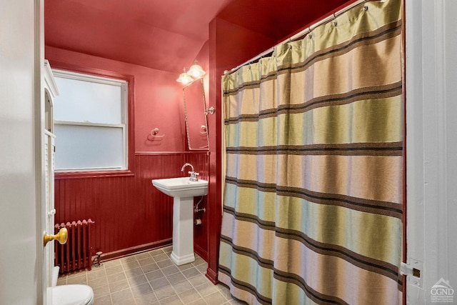 bathroom featuring a shower with shower curtain, toilet, radiator heating unit, and sink