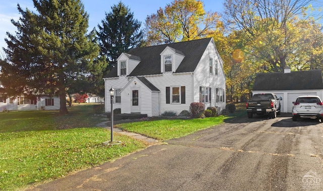 new england style home with an outbuilding, a front yard, and a garage