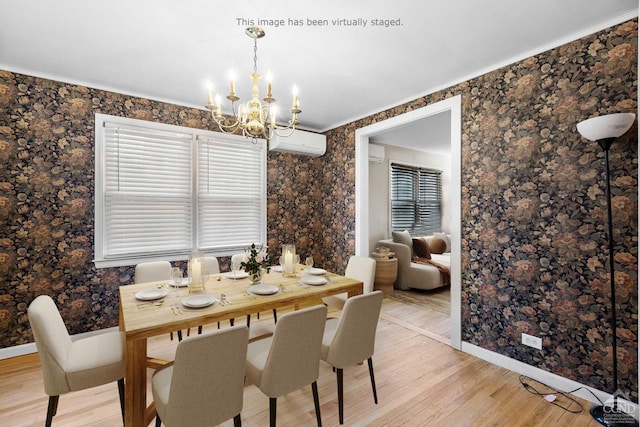 dining area featuring baseboards, a wall unit AC, a chandelier, and light wood finished floors
