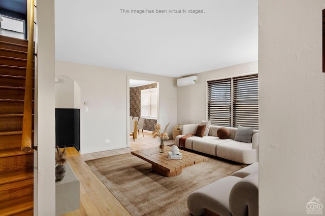 living room with a wall mounted air conditioner and light hardwood / wood-style floors