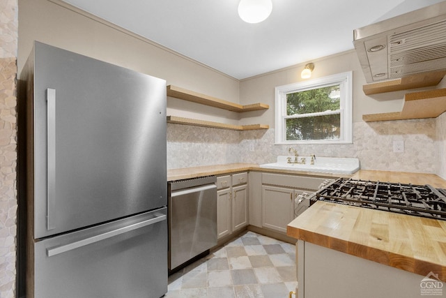 kitchen featuring backsplash, butcher block counters, sink, and appliances with stainless steel finishes