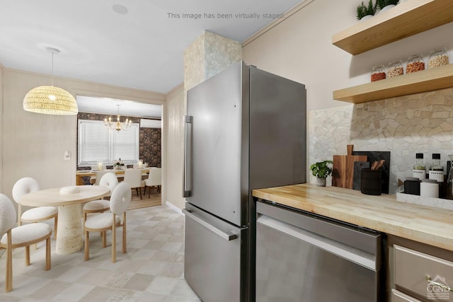 kitchen with wood counters, an inviting chandelier, a fireplace, appliances with stainless steel finishes, and decorative light fixtures