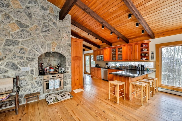 kitchen with vaulted ceiling with beams, kitchen peninsula, appliances with stainless steel finishes, wood ceiling, and light wood-type flooring