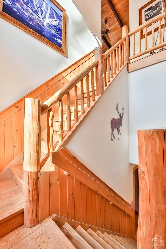 staircase featuring wooden ceiling, a high ceiling, and wooden walls