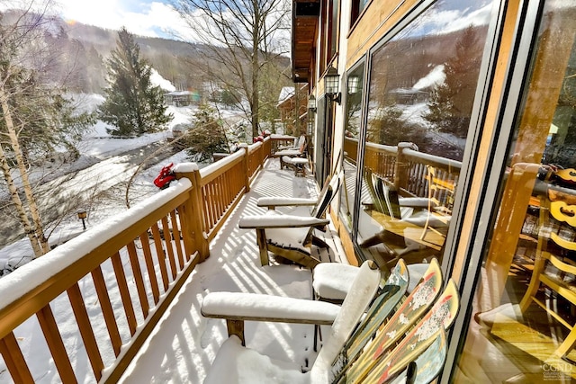 snow covered back of property featuring a mountain view