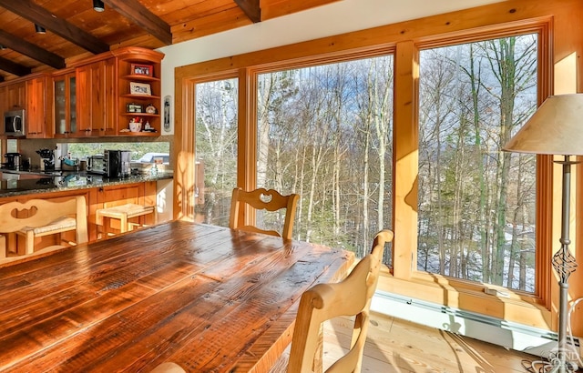 dining room with beamed ceiling, a baseboard radiator, light hardwood / wood-style flooring, and wooden ceiling