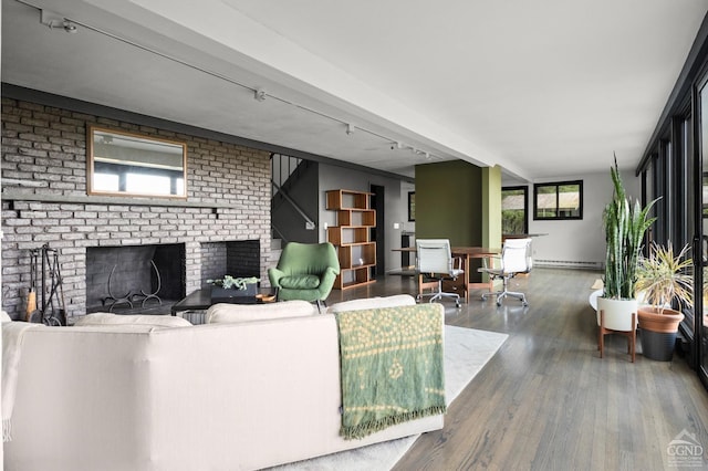 living room featuring hardwood / wood-style flooring, a fireplace, a healthy amount of sunlight, and baseboard heating