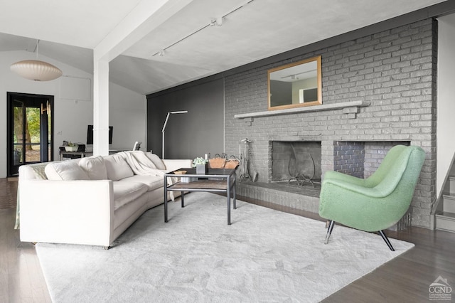 living room with hardwood / wood-style floors, vaulted ceiling, and a brick fireplace